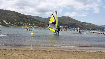 Una playa con gente practicando windsurf y nadando.
