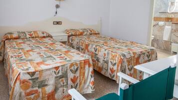 Una habitación con dos camas individuales, una mesita, una silla y un baño con pared de mármol.