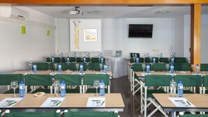 Un salón de conferencias con mesas dispuestas para reuniones, equipado con botellas de agua, vasos y tarjetas de identificación.