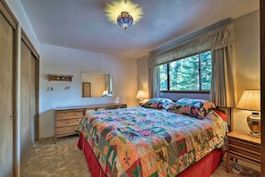 Un dormitorio con una cama grande, un aparador, un espejo y una ventana con cortinas.