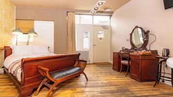 Une chambre à coucher avec un lit en bois, un banc, un bureau, une chaise, un miroir et un radiateur.