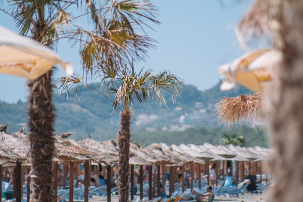 Pantai pribadi, pasir putih, kursi berjemur, dan payung pantai