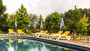 Un espace aménagé au bord de la piscine, avec des chaises longues et des serviettes, une piscine à eau claire et des drapeaux.