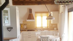 A spacious kitchen with white cabinets, a dining table with chairs, and a hanging light fixture. - villa in the green | street number 2 (uzzano)