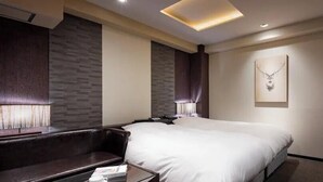 Ein Hotelzimmer mit einem großen Bett, einer Sitzecke mit Tisch und einem an der Wand montierten Fernseher.