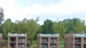 Een rij identieke gebouwen met balkons, gelegen aan een rustig waterlichaam, omgeven door groen.