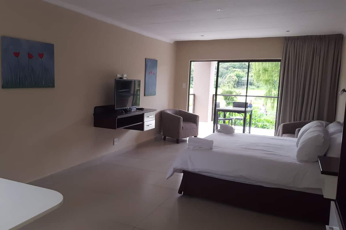 A hotel room with a bed, a desk, a chair, a TV, and artwork on the walls.
