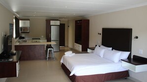 Een hotelkamer met een bed, een bureau, een kitchenette en een televisie.