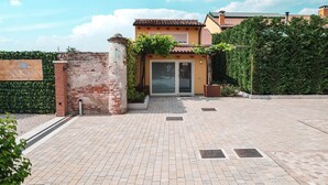 A hotel entrance with a paved driveway, a brick pillar, and a signboard. - Little House (Campo San Martino)