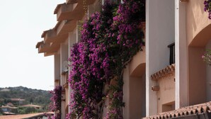 A building with balconies covered in purple flowers, white walls, and a tiled roof. - Residence Pinnetta - 4-seater apartment with free pool and WiFi (Arzachena)