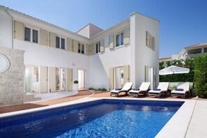 A modern building with a swimming pool, lounge chairs, and a patio area. - Villa Cipriana (Tar-Vabriga)