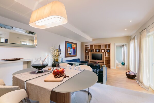 A modern living room with a dining area, a TV, and a large window with curtains. - Villa Cipriana (Tar-Vabriga)