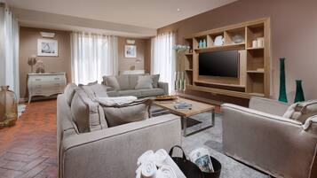 A modern living room with a sofa set, a coffee table, a flat-screen TV, and a fireplace.