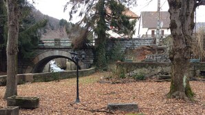 Un puente de piedra sobre un arroyo, rodeado de árboles y muros de piedra.
