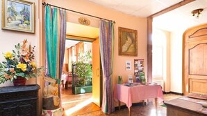 Una habitación con puerta de madera, una mesa con mantel rosa y un jarrón de flores.