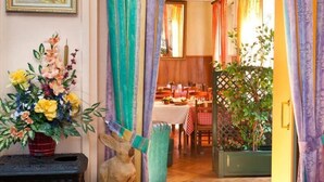 Un comedor con una mesa dispuesta para dos personas, una planta en maceta y un cuadro en la pared.
