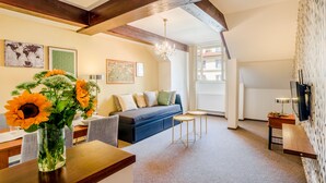 A modern living room with a sofa, a coffee table, and a vase of sunflowers. - Apartment Charles Bridge (Prague)