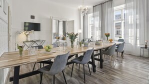 A modern dining area with a long wooden table, grey upholstered chairs, and a chandelier. - Historic Centre APTs by Michal&Friends (Prague)