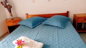 A neatly made bed with a blue quilt, two pillows, and a towel with a flower. - Akropolis Studios (Agios Vasileios)