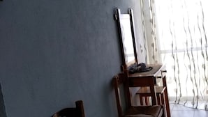 A room with a television mounted on the wall, a dining table with chairs, and a window with curtains. - Akropolis Studios (Agios Vasileios)