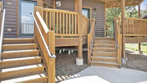 Eine Holztreppe führt zu einem überdachten Außenbereich mit einer Holzterrasse und einer Tür mit der Aufschrift "26C".