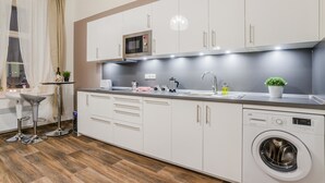 Una cocina moderna con armarios blancos, microondas integrado, pileta y lavadora.