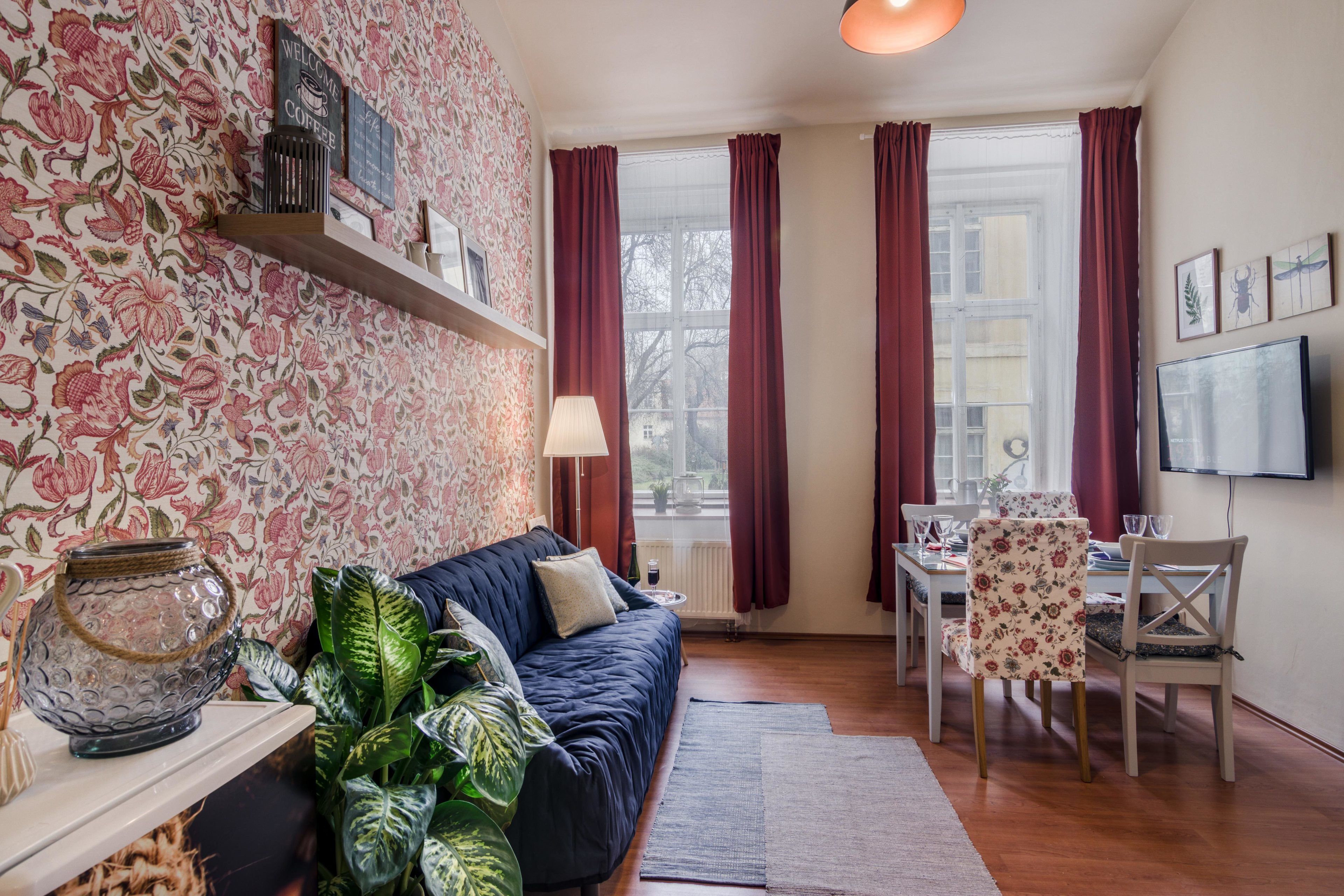 Una sala de estar acogedora con un sofá azul oscuro, una mesa de centro y un comedor con sillas estampadas.
