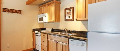 A kitchen with wooden cabinets, a white refrigerator, a dishwasher, a stove, and a microwave.