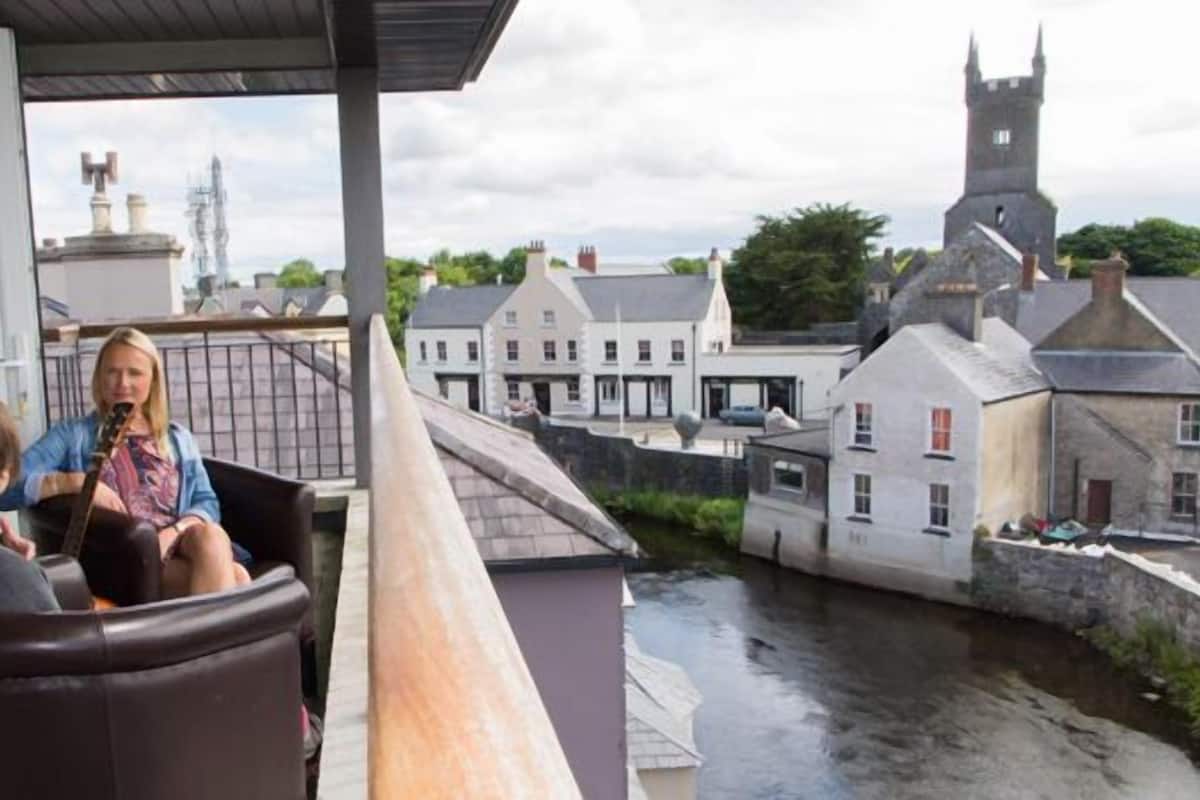 A balcony with a view of a canal and historic buildings, including a tower.