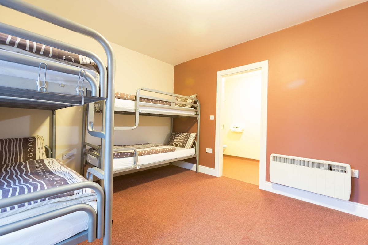 A bunk bed room with a radiator and a door.
