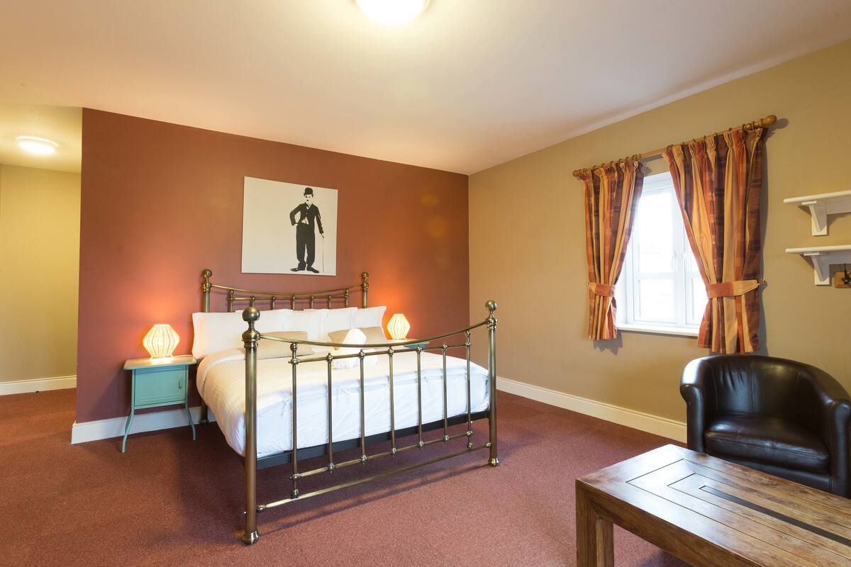 A bedroom with a bed, bedside tables, a chair, and a window with curtains.