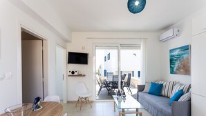 A modern living room with a sofa, a dining table, and a TV mounted on the wall. - Triton Sea View 7 - two bedroom house close to the sandy beach (Asprouliani)
