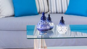 A glass-top coffee table with decorative vases and a striped sofa with blue cushions in the background. - Triton Sea View 7 - two bedroom house close to the sandy beach (Asprouliani)