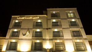 A modern building with illuminated signage and windows. - Lujain Hotel Suites (Amman)
