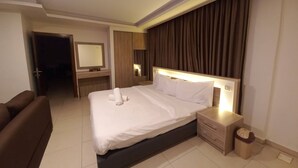 A hotel room with a bed, bedside tables, a mirror, a dresser, and a door leading to another room. - Lujain Hotel Suites (Amman)