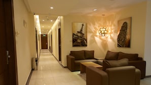 A hotel lobby with a long corridor, sofas, and artwork on the walls. - Lujain Hotel Suites (Amman)