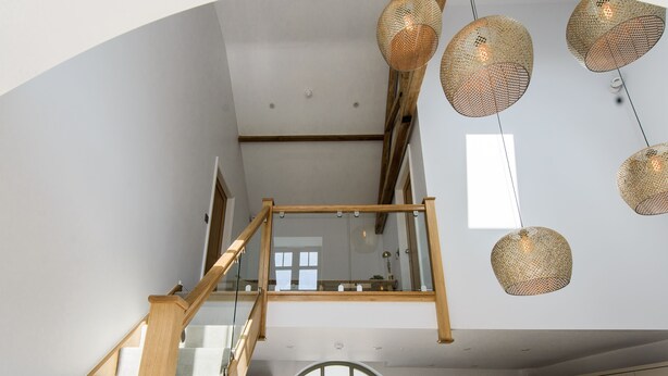 A modern kitchen with a dining area, a staircase with glass railings, and hanging wicker light fixtures. - The Gables - 2 bedroom self catered cottage apartment (BARNETBY)