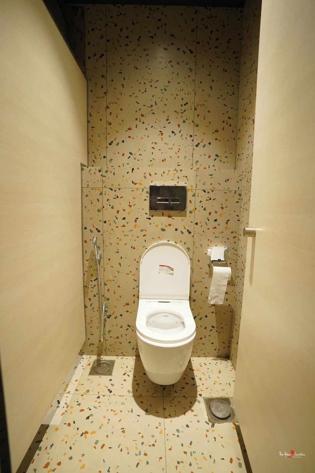A small, compact bathroom with a white toilet, a hand dryer, and a paper towel dispenser.