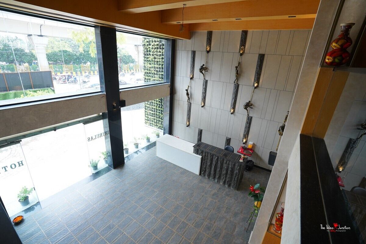 A hotel reception area with a modern design, including a reception desk, a wall with decorative elements, and a view of the street outside.