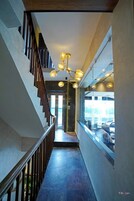 A modern interior with a staircase, a unique chandelier, and a view through a glass wall.