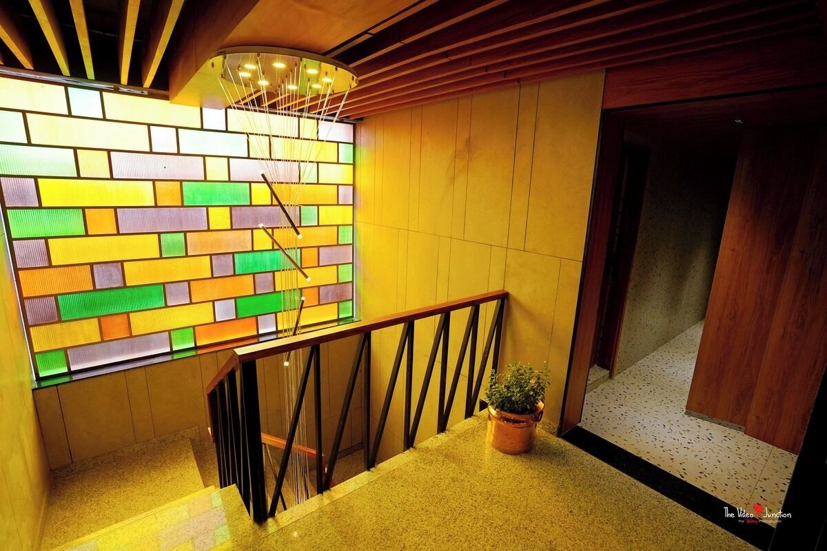 Una escalera con un muro de ladrillos de colores, barandilla de madera y una planta en maceta.