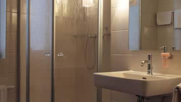 Un baño moderno con ducha de vidrio, lavabo con espejo y una toalla colgada en la pared.