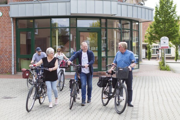 A group of people on bicycles in front of a building with a curved glass entrance.