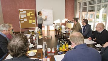 Una sala de reuniones con pizarra, tablón de anuncios y una mesa con bebidas y documentos.