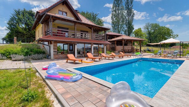 Une maison à deux étages dotée d’une piscine, d’un espace extérieur aménagé et offrant une vue sur le paysage environnant.