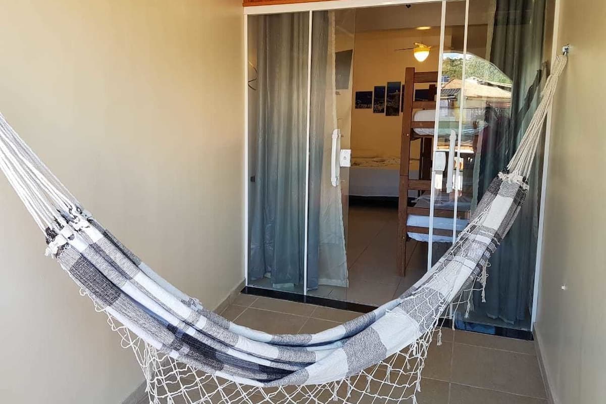 A hammock in a room with a sliding glass door leading to a balcony.