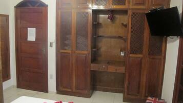 Une chambre avec un lit, une armoire en bois et un téléviseur fixé au mur.