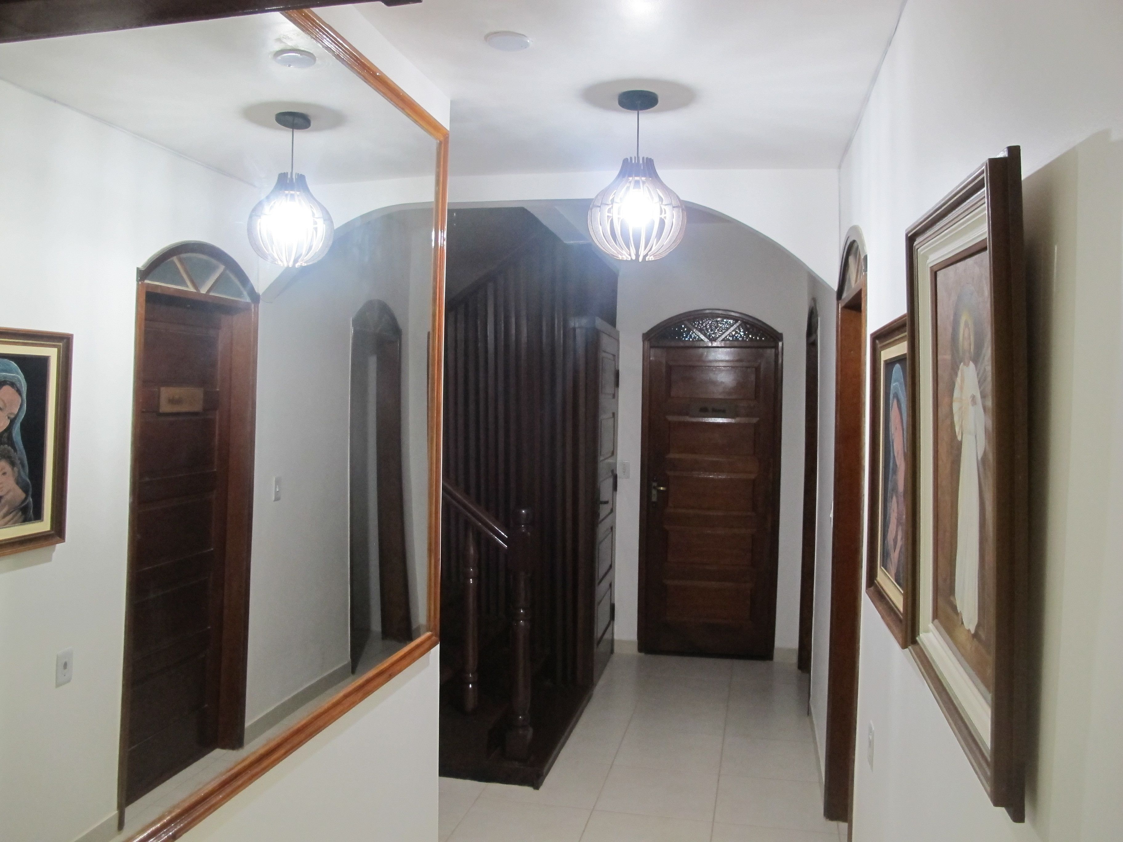 Un pasillo con puerta de madera, un espejo y una lámpara.