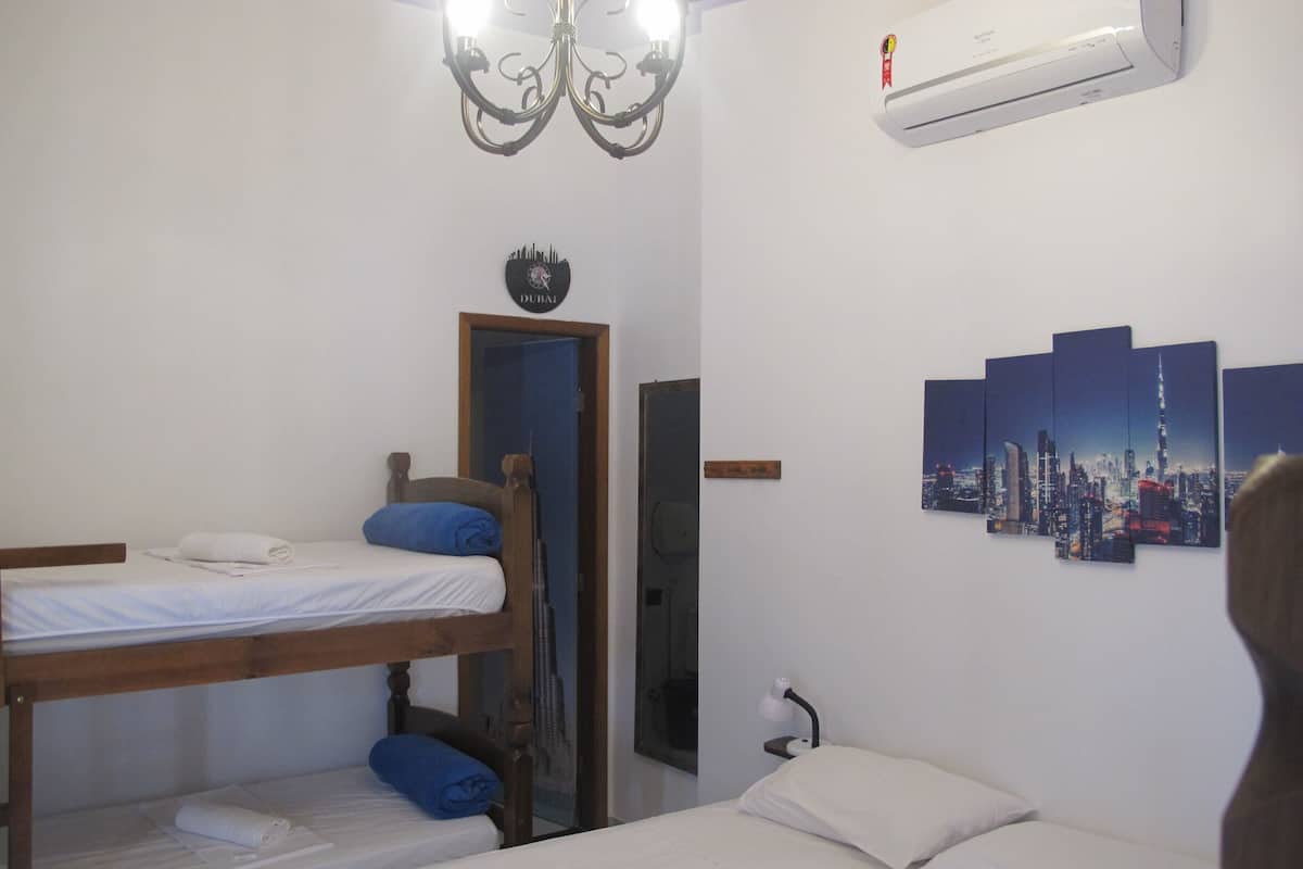 A room with bunk beds, a cityscape wall art, an air conditioning unit, and a chandelier.