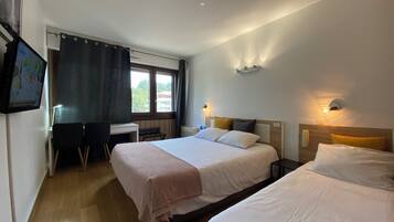 A hotel room with two beds, a desk, and a TV.